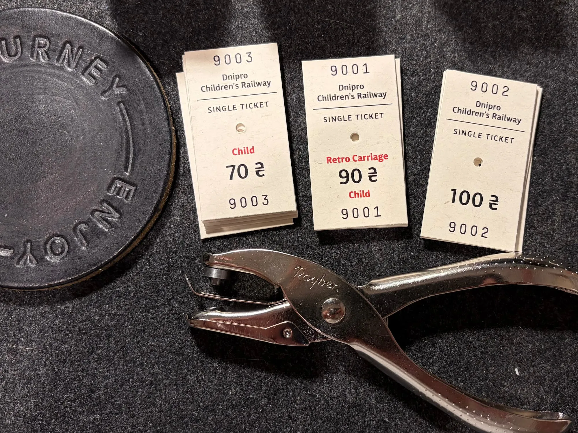 Three stacks of finished tickets, numbered from 9001, next to a metal hand puncher