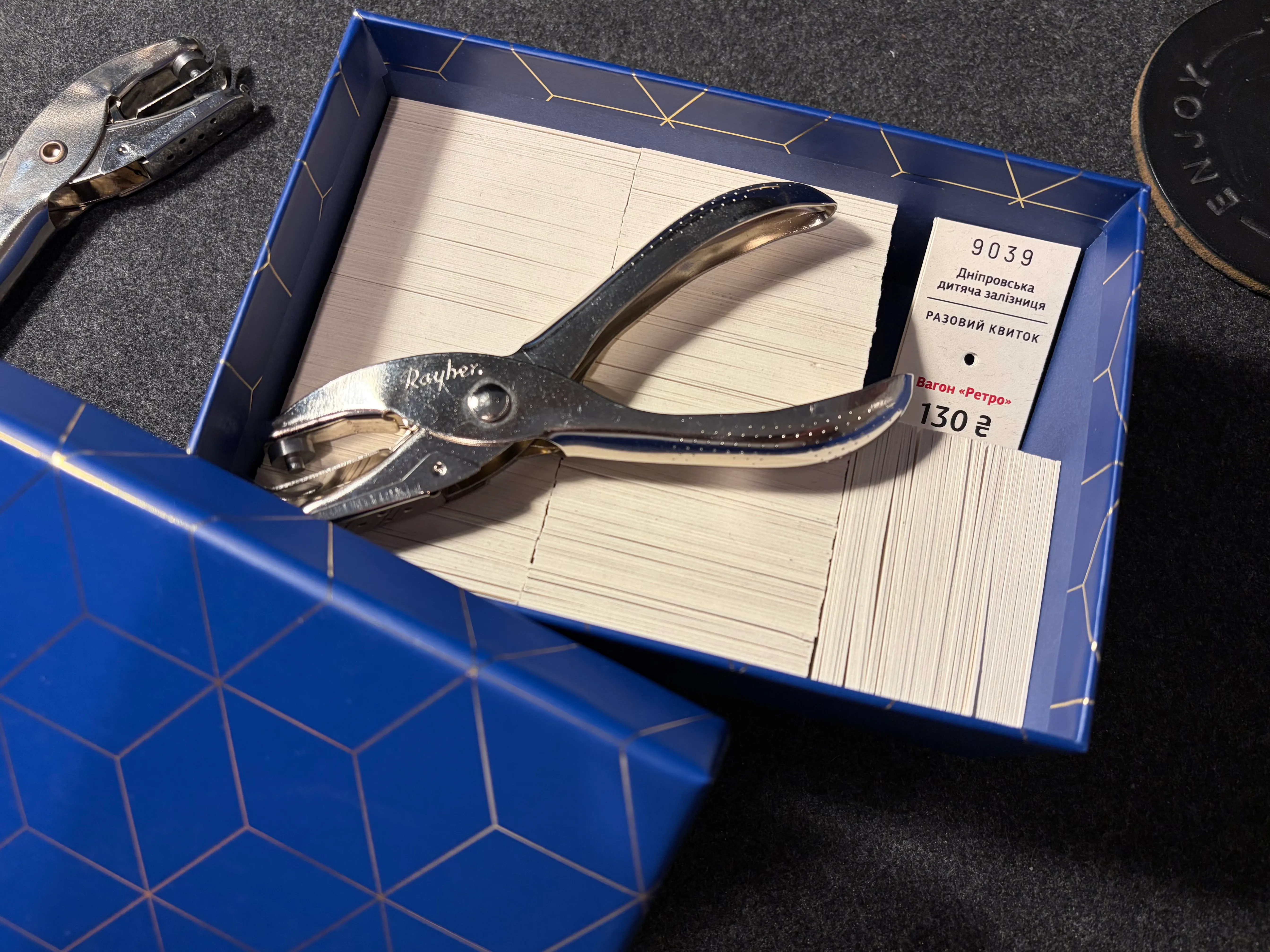 All 300 tickets packed edge-up in a blue gift box, with a hand puncher resting on top and one ticket peeking out