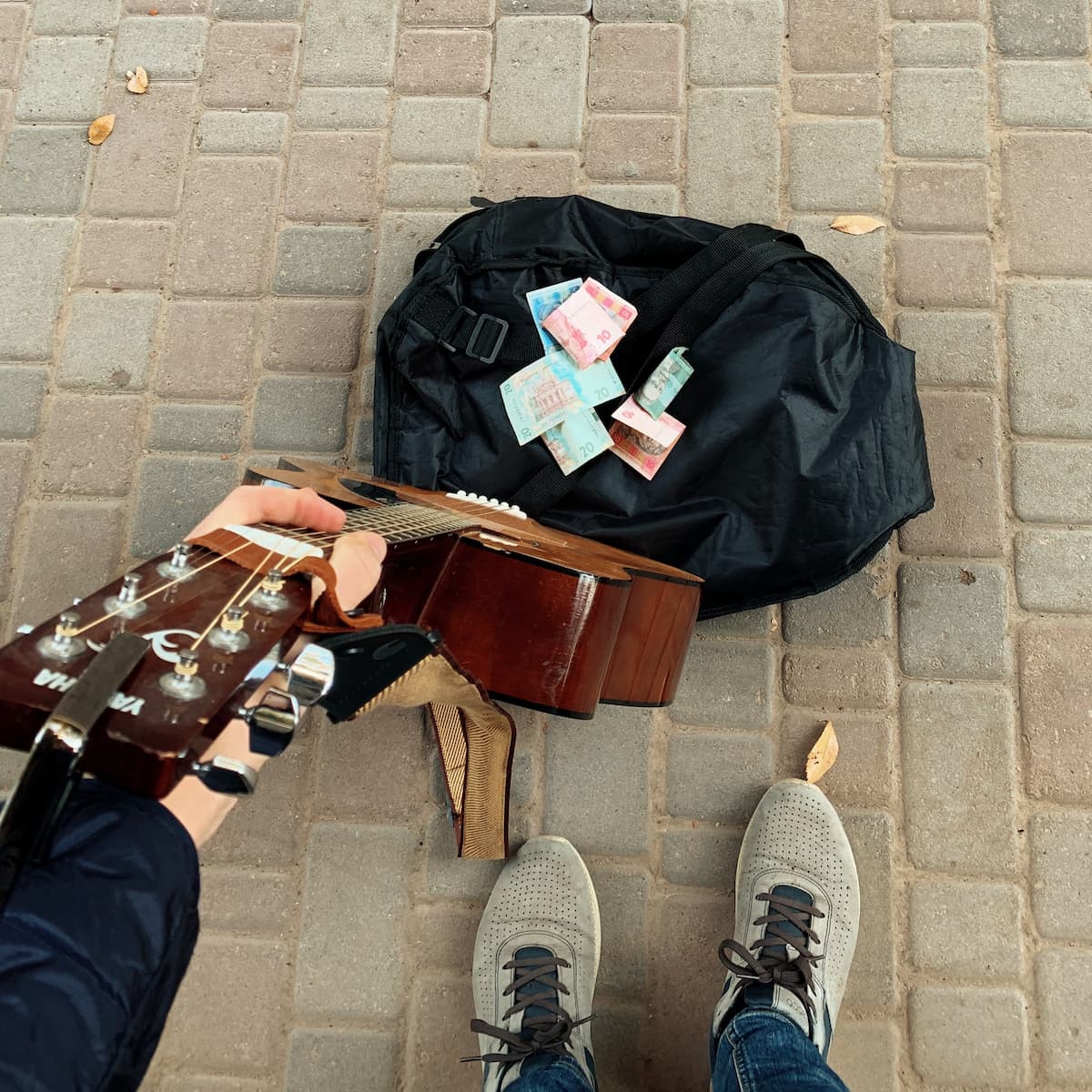 A photo that shows my guitar and black bag on a sidewalk.