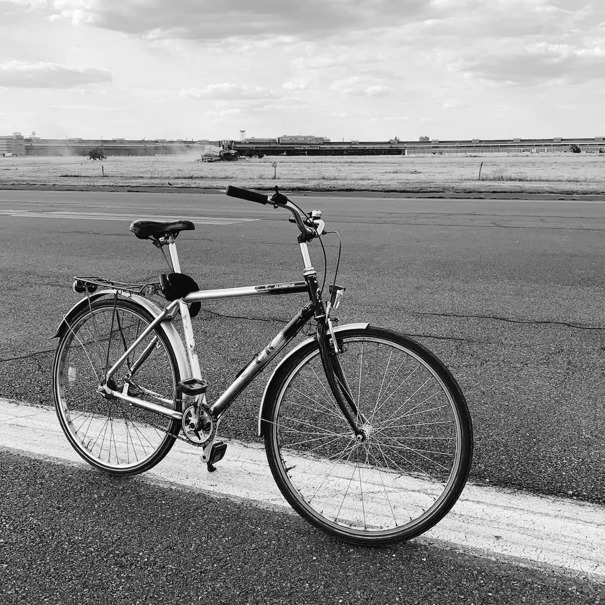 A black-and-white photo of a bicycle standing on the Tempelhof Airport runway